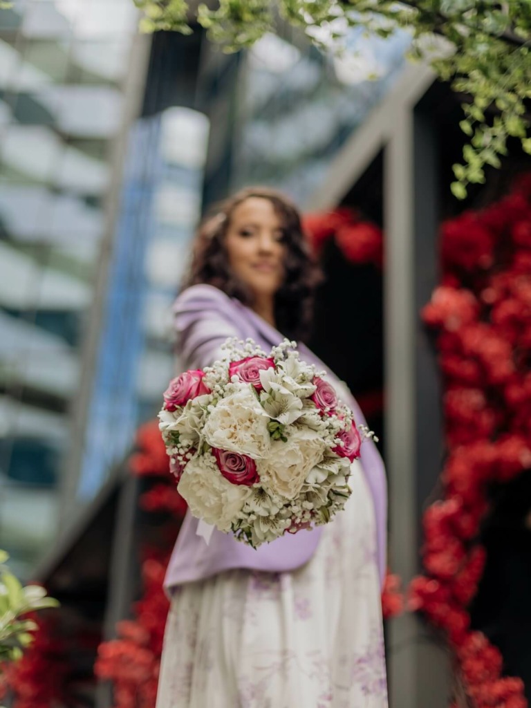Fotografske usluge - Novi Sad 2 Mlada ponosno pokazuje bidermajer ispred kamere, zabeleženo tokom modernog venčanja u Novom Sadu.
